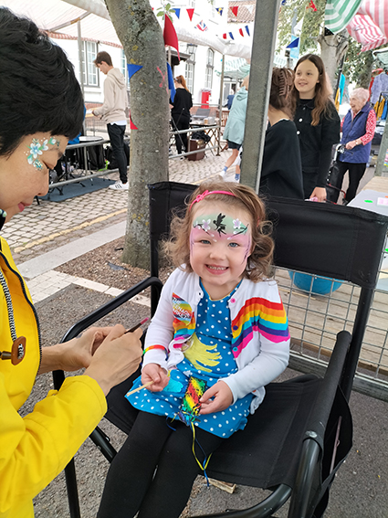 A smiley young girl getting her face painted